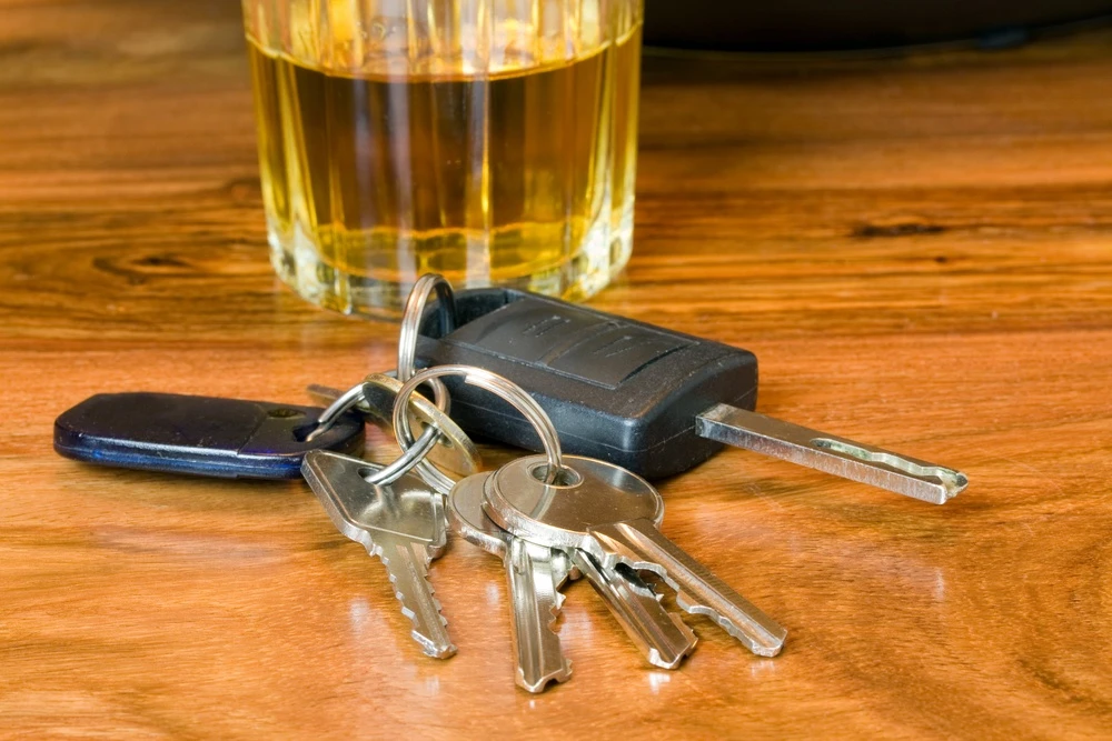 a set of car keys next to an alcoholic beverage