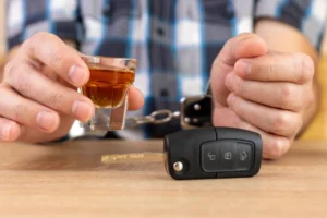 a person in handcuffs holding a shot glass and car keys