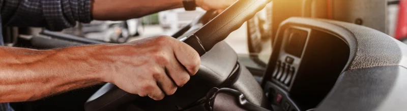 CDL driver with his hands on the wheel of a semi-truck