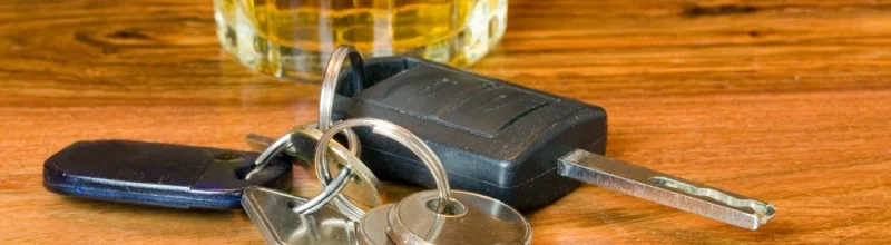 a set of car keys next to an alcoholic beverage